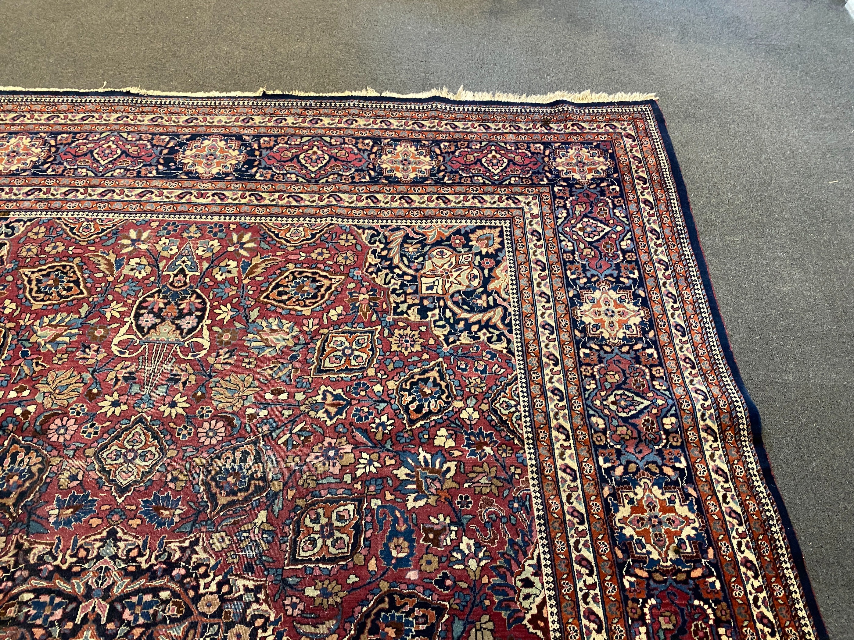 An early 20th century Heriz burgundy ground carpet, 412 x 305cm